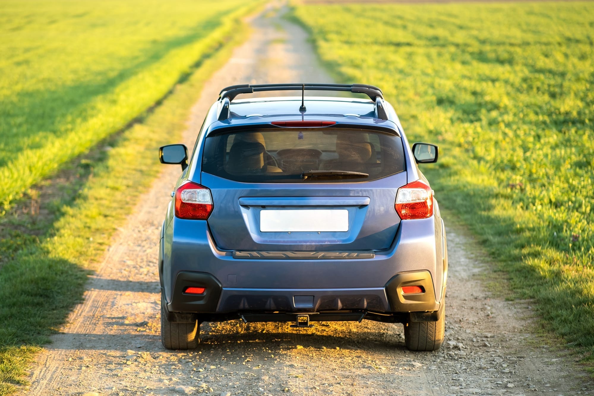 "A small blue car on a narrow country lane"